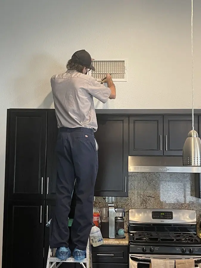 Technician inspecting an air vent during HVAC service in West Falls Church